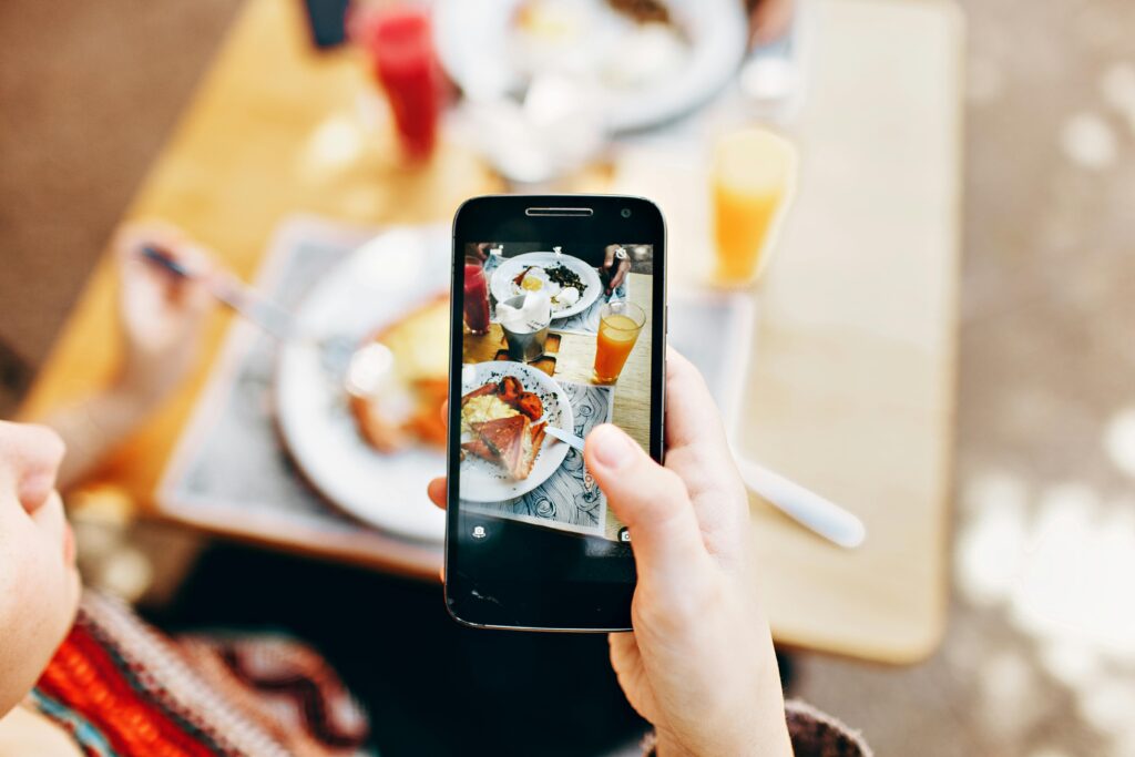 a hand holding a phone that is taking a picture of food