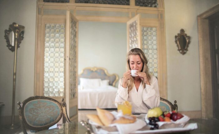 a woman sitting at a table with a tray of food and a cup of coffee