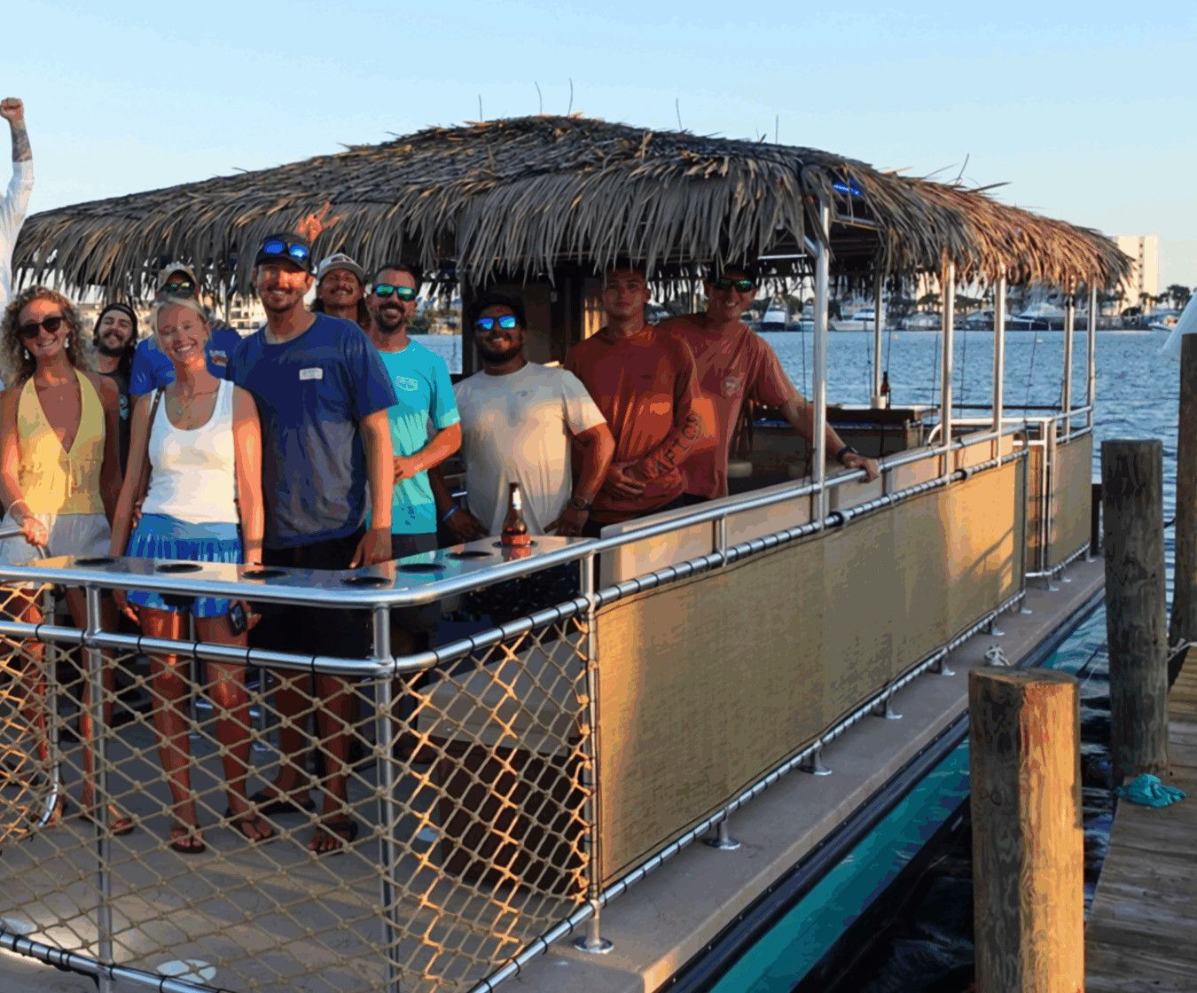 A group of guests in summer clothes aboard The Tipsy Tiki boat at the dock in Destin